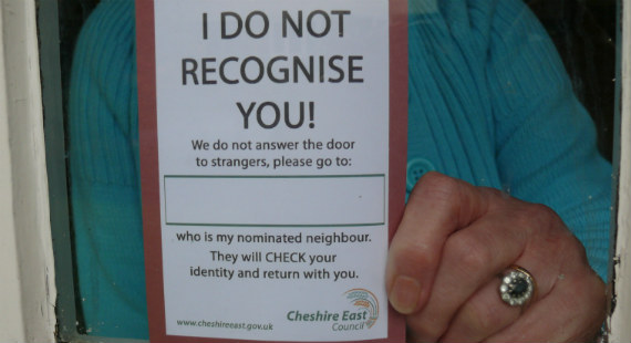 A woman holds up a nominated neighbour scheme card