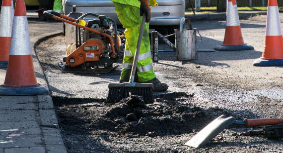 A Cheshire East Council Highways employee works on a pothole
