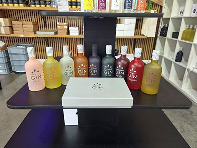 Selection of colourful Three Wrens Gin bottles displayed on a table in the gift shop at The Three Wrens Gin distillery in Cheshire East, with boxed gift sets behind.