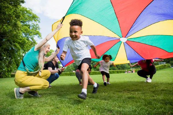Children running under a brightly coloured sheet
