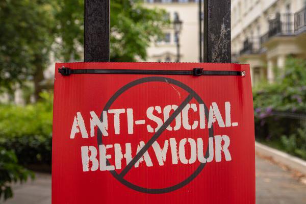 A red sign that states no anti-social behaviour in white text