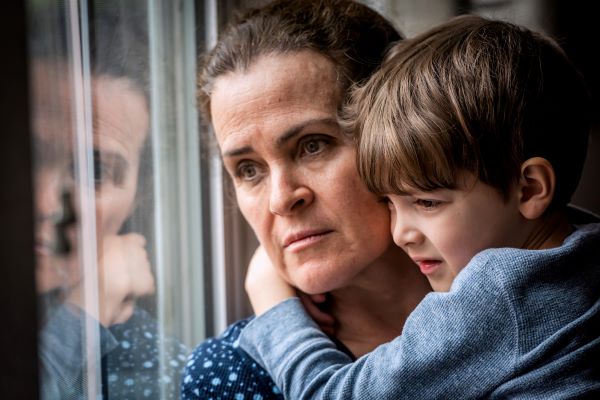 A woman looking out of the window holding a child