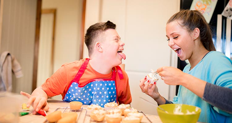 A boy with down syndrome bakes cakes with his sister in the kitchen.