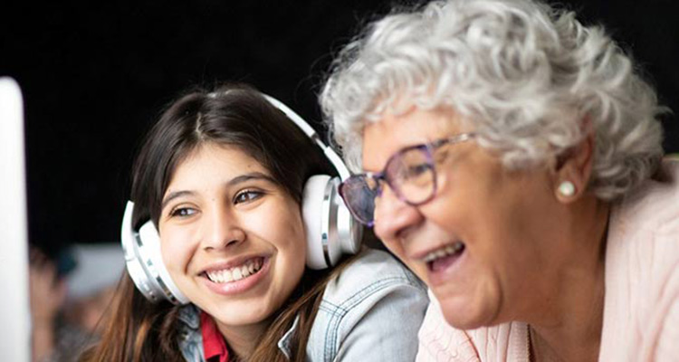 A child and older adult looking at a computer screen and smiling