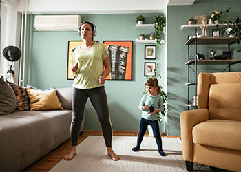 Adult woman dancing at home during quarantine with three year old daughter