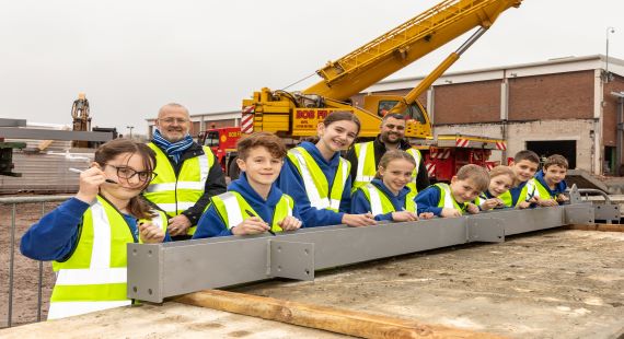 Children sign a steel beam at leisure centre site