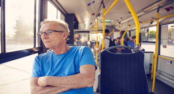 Older man on bus in blue T shirt relaxing 570 x 310