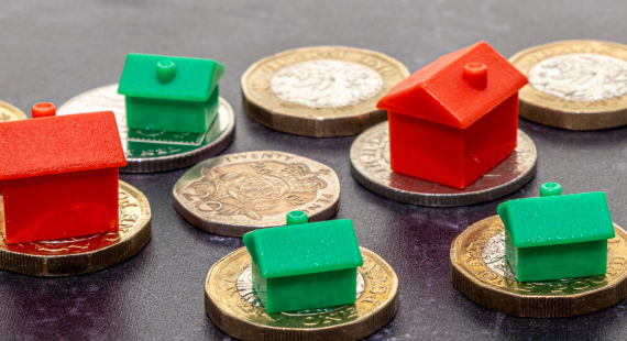 Pound coins and monopoly houses on a black background