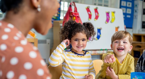 Two smiling children at a table in a nursery setting