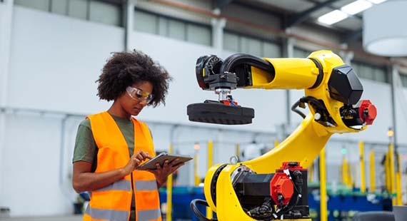 A woman in hi-vis next to a yellow robotic arm