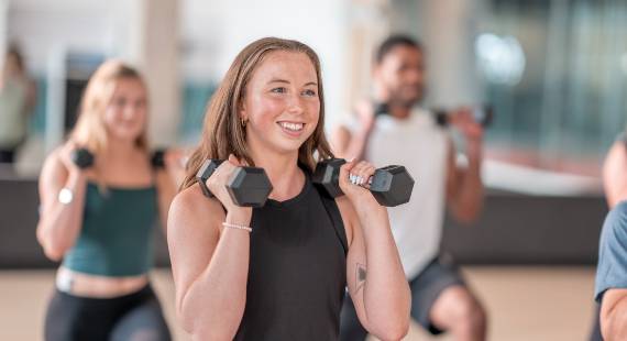 A woman holding weights during an exercise class. Other participants are in the background.