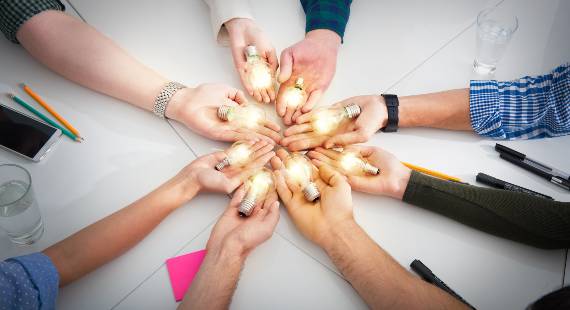 hand coming together and holding lightbulbs to signify innovation and collaboration