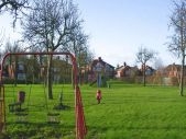 Swings and field at Stallard Way play area in Middlewich.
