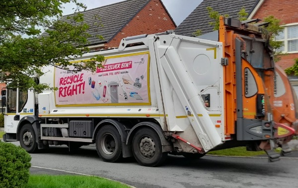 Photo of a waste vehicle collecting waste on a street